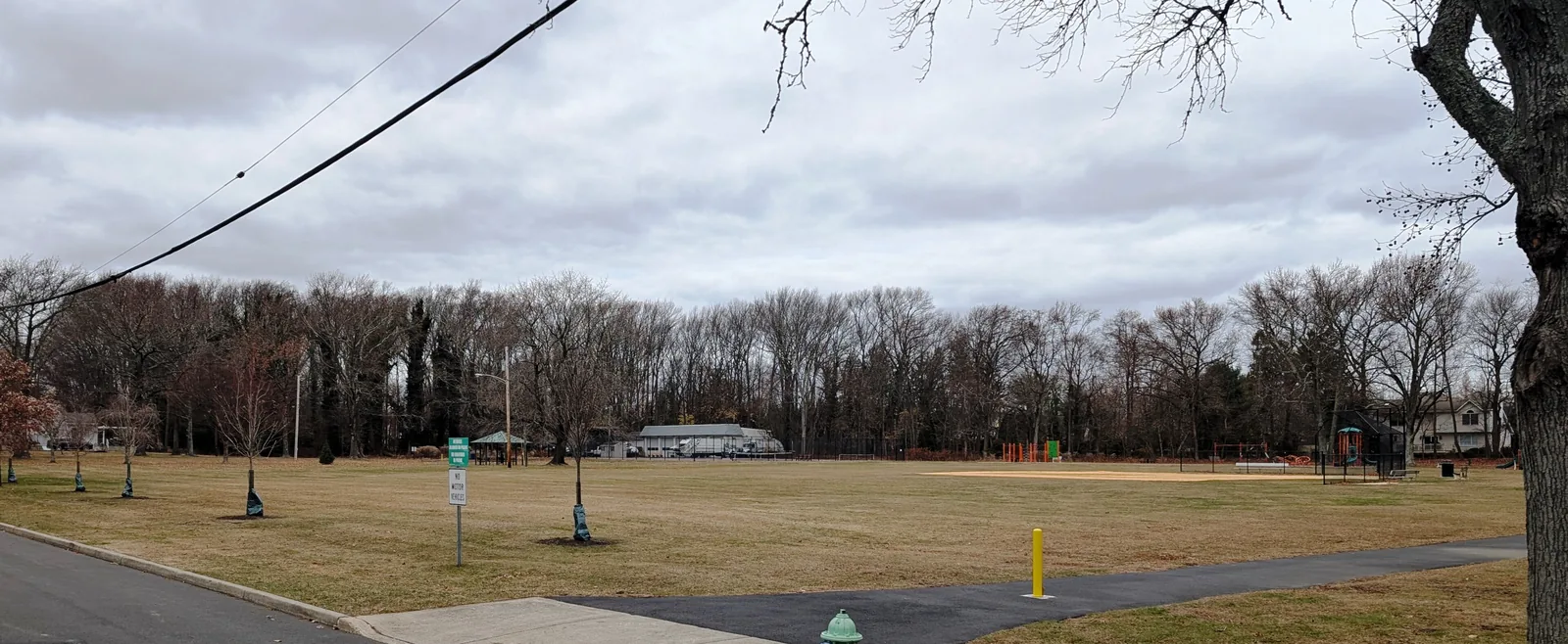 The open lawn, ballfield and playground of Interlaken Park framed by bare winter trees