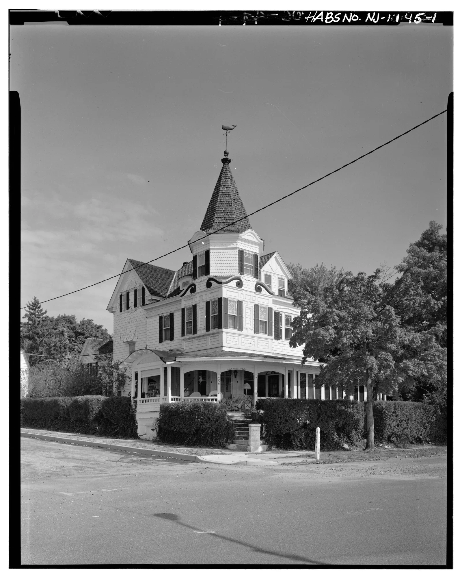 Black and white photo of the Island Queen House, a Victorian home with a tall pointed turret and wraparound porch