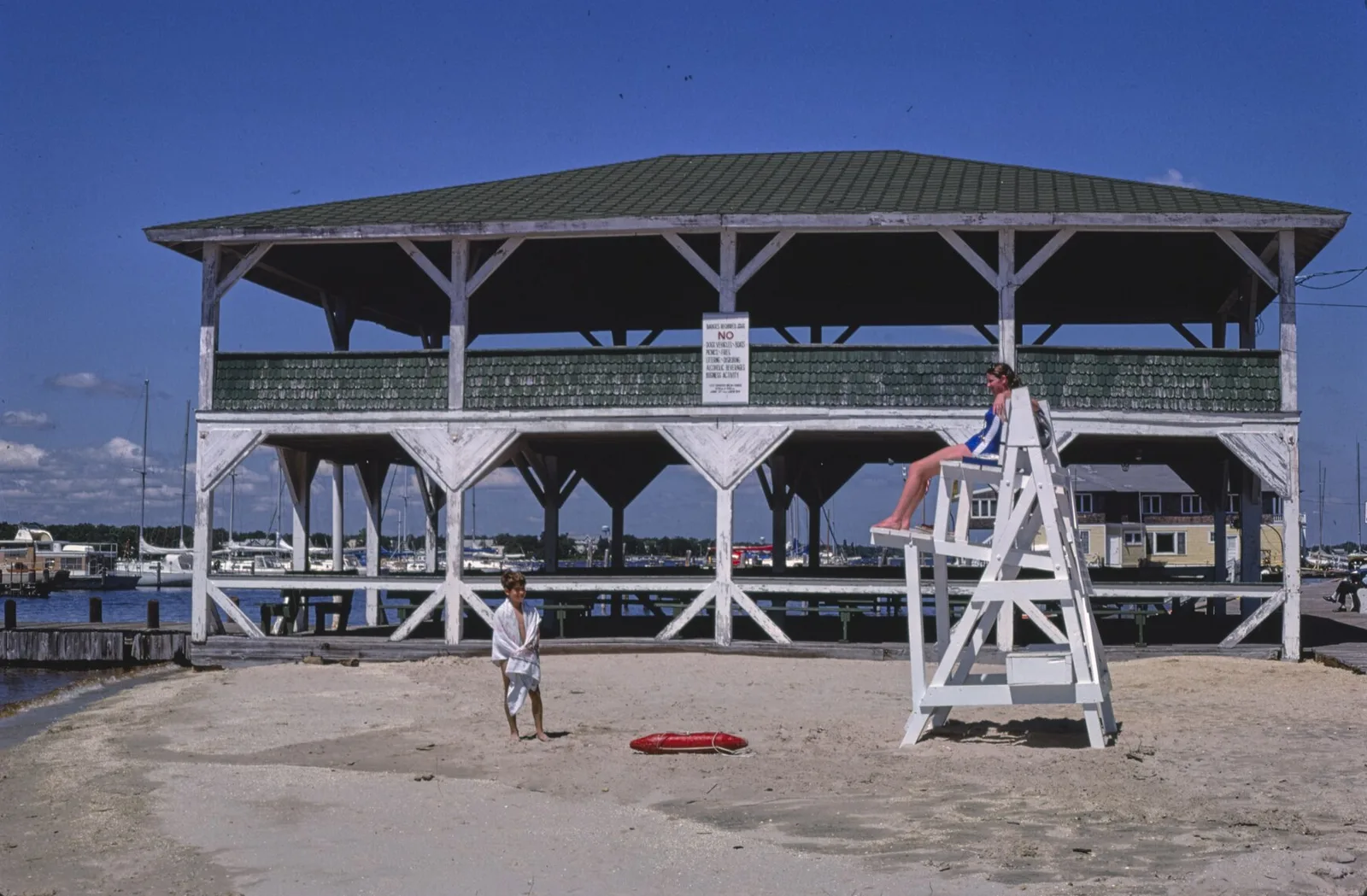 A two-level wooden beach pavilion and lifeguard stand on the Island Heights riverfront, boats beyond, photographed in 1978