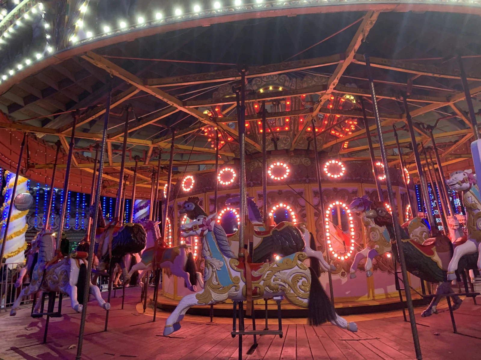 Carousel horses under rings of red and white lights during Holiday in the Park