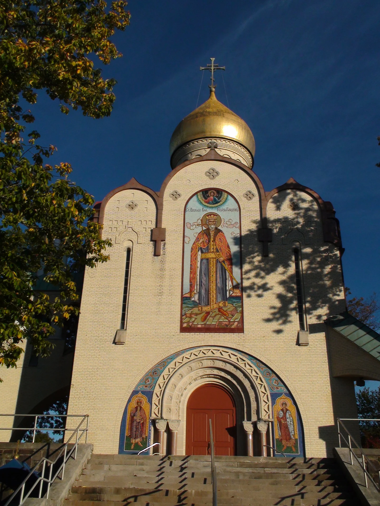 White St. Vladimir Memorial Church with a golden onion dome and a painted icon above its arched doorway