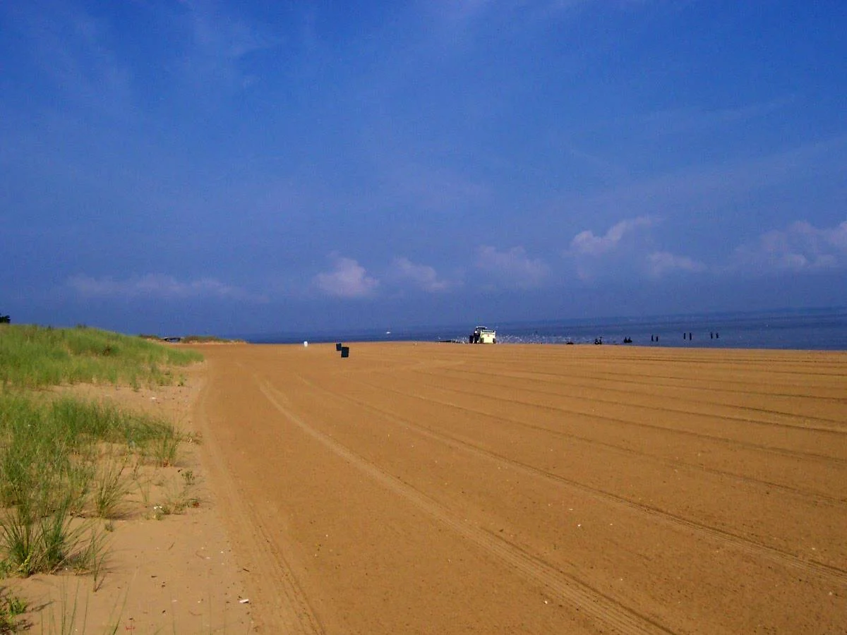 The wide sand beach on Raritan Bay in Keansburg in early morning light, dune grass on the left