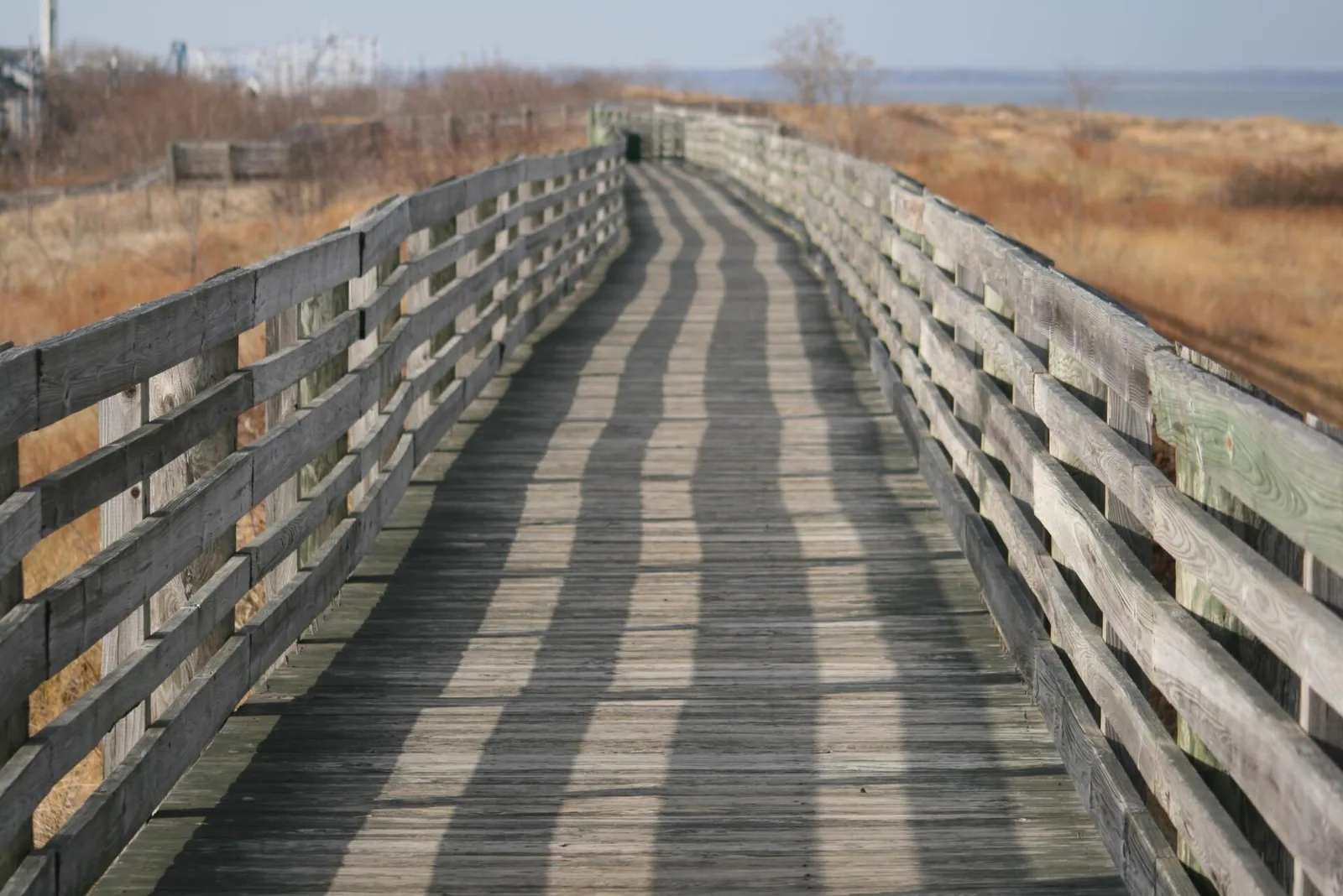 A weathered wooden Bay Walk leading through dune grass toward Raritan Bay in Keansburg