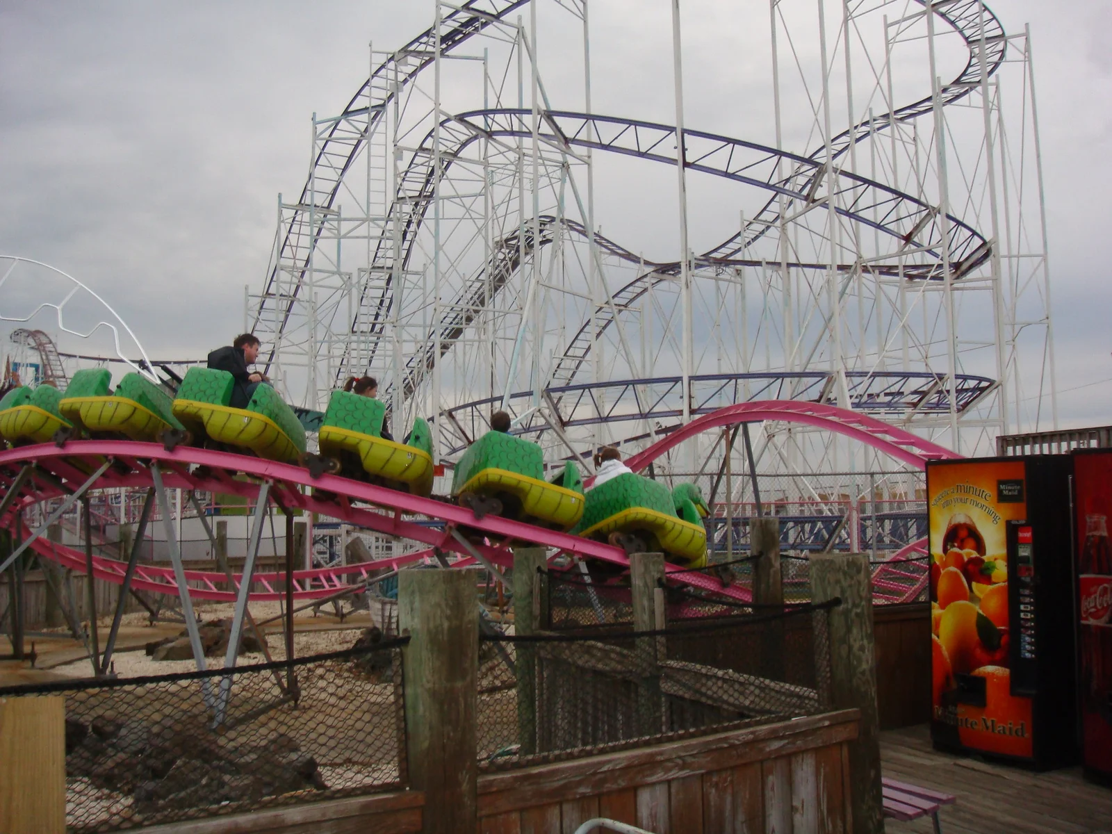 Riders in green cars on a roller coaster at Keansburg Amusement Park, white coaster track looping overhead