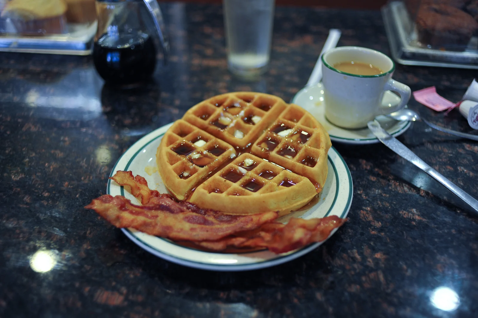 Golden waffle with strips of bacon and a cup of coffee on a granite table at the Lakehurst Diner