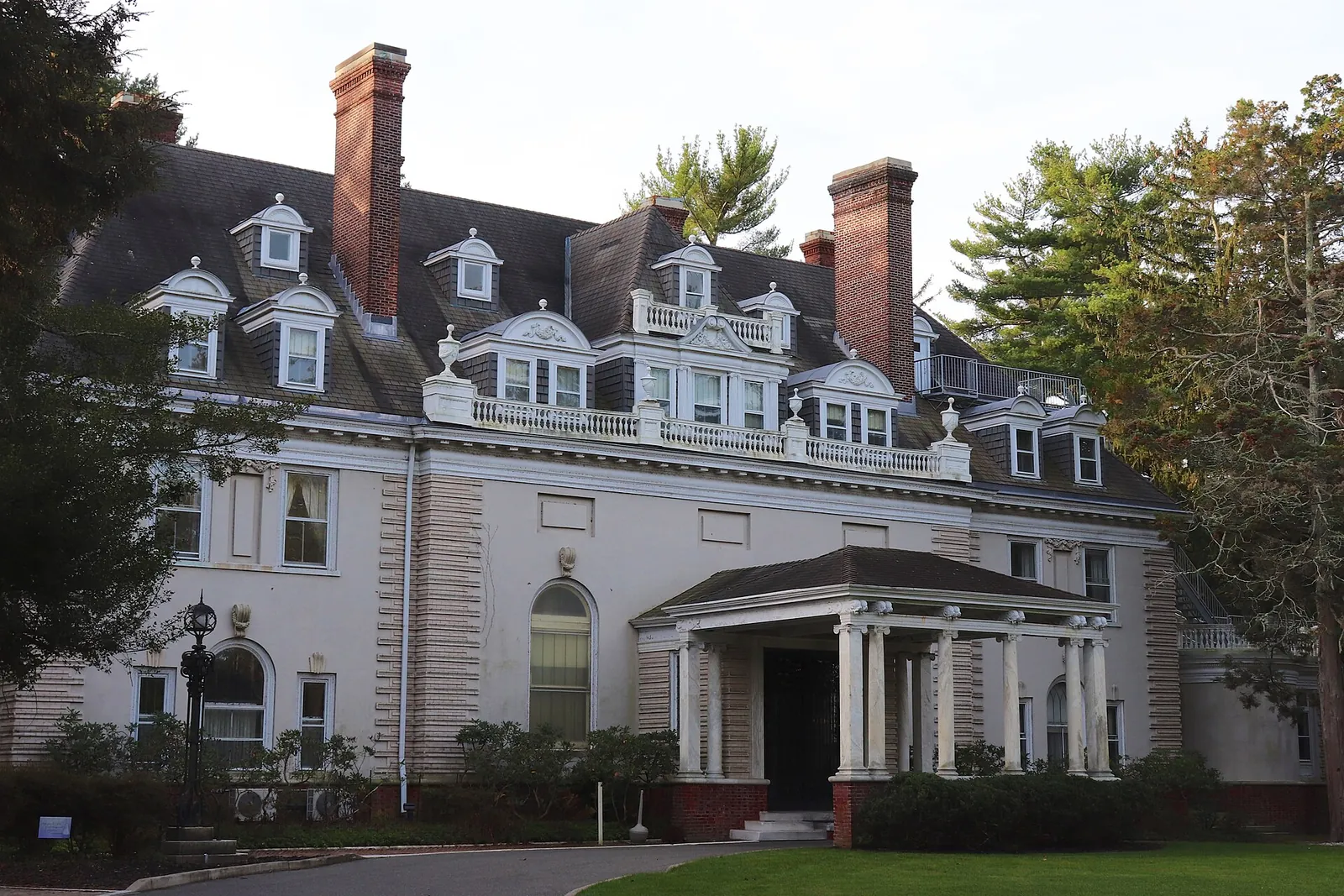 The white Gould mansion at Georgian Court University with dormer windows, tall chimneys and a columned entrance