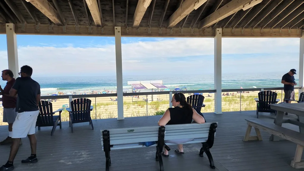 The covered deck of the Brant Beach pavilion with benches and Adirondack chairs looking over the dunes to the ocean