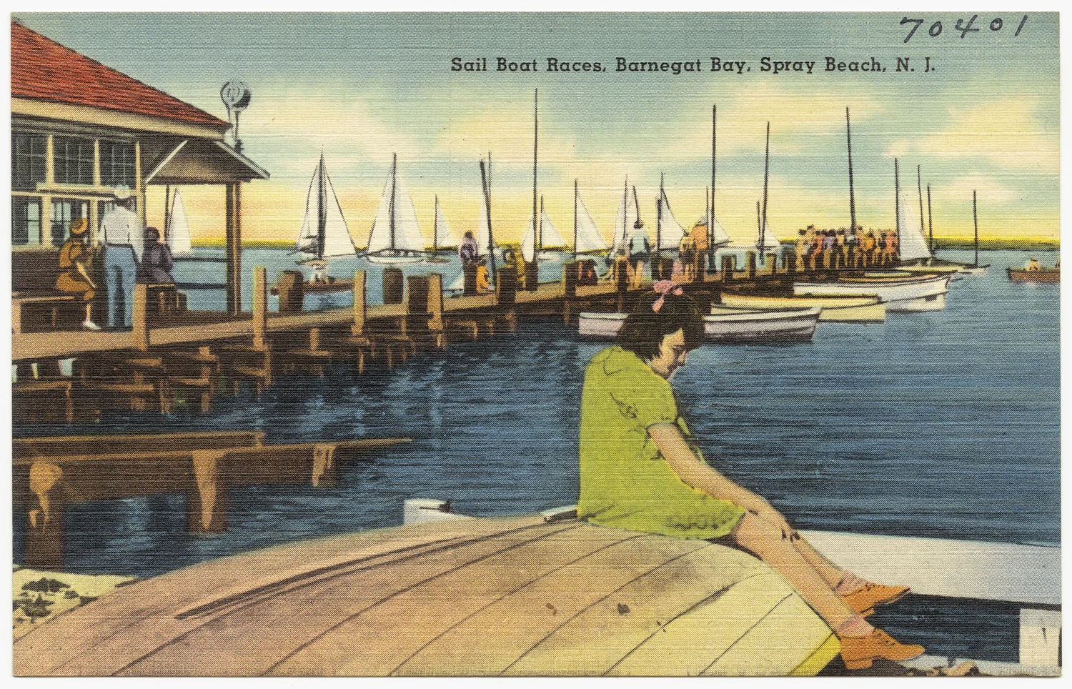 Vintage linen postcard of a woman in a green dress sitting on an overturned boat by a dock crowded with sailboats on Barnegat Bay