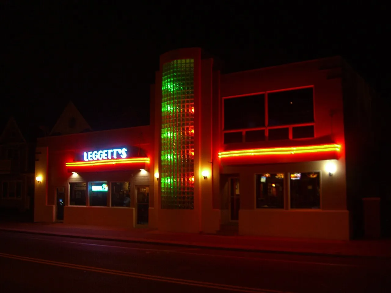 Art deco style bar building glowing with red and green neon at night