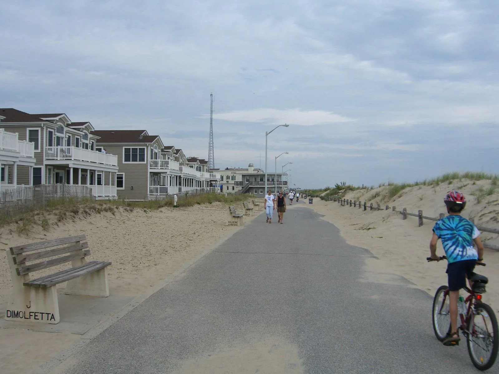 The Manasquan boardwalk path running between beachfront homes and the dunes, with benches along the way