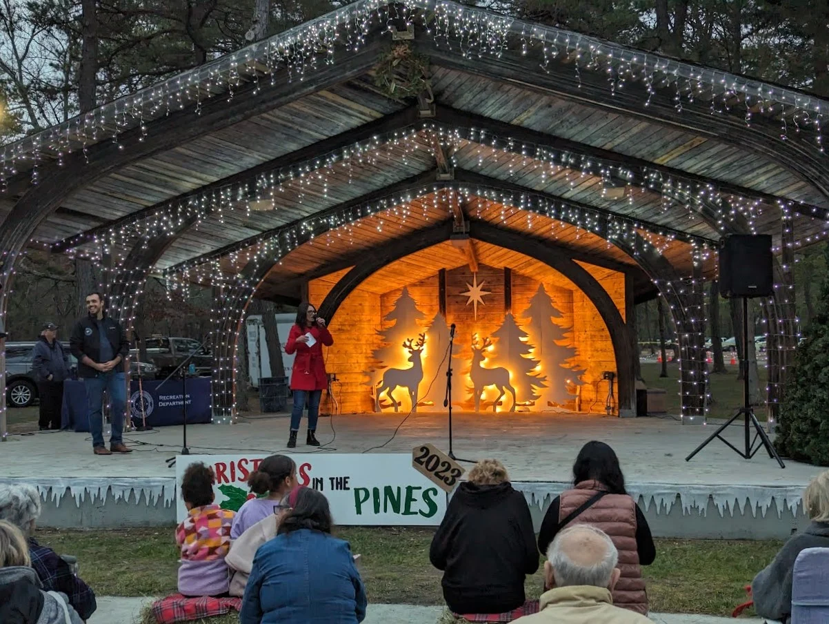 The Harry Wright Lake bandshell outlined in white lights with a glowing winter scene, and an audience seated in front