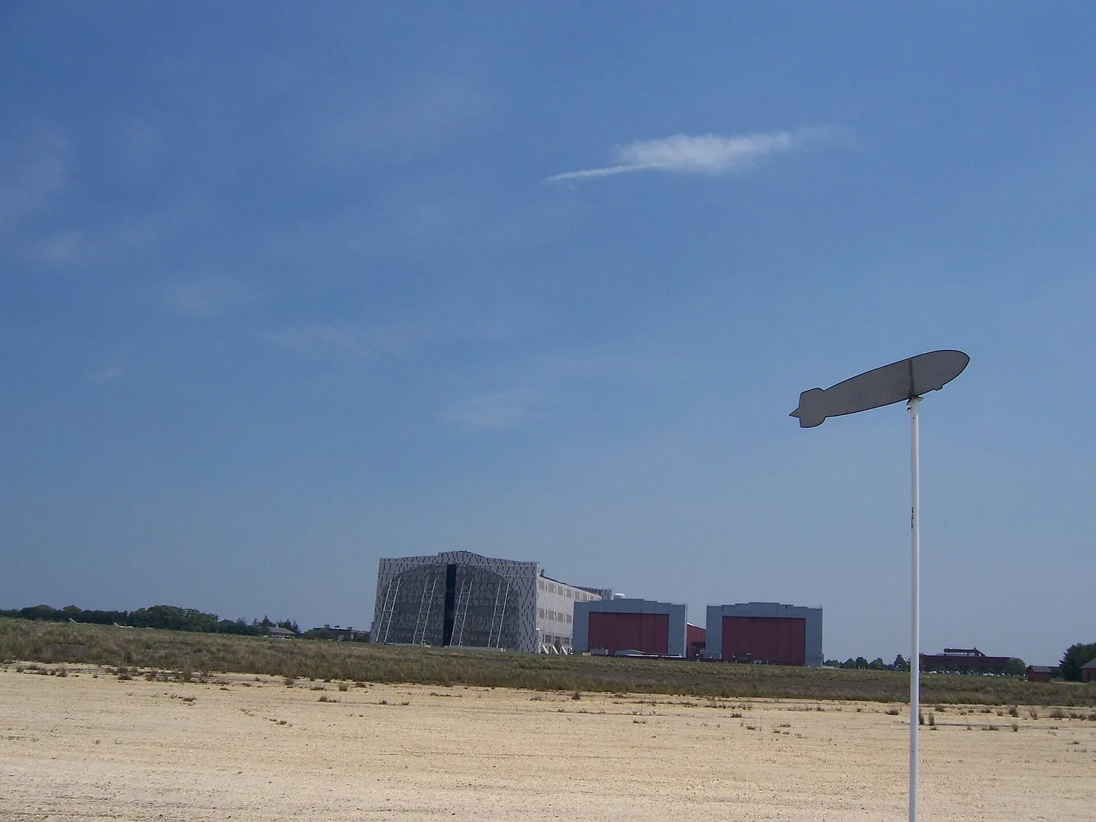 The airship-shaped marker at the Hindenburg crash site, with the giant Lakehurst hangars on the horizon