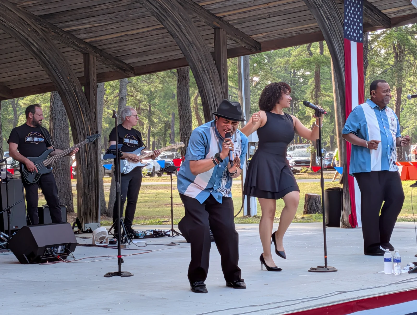 Singers and a band perform on the bandshell stage under the pines at Manchester Day