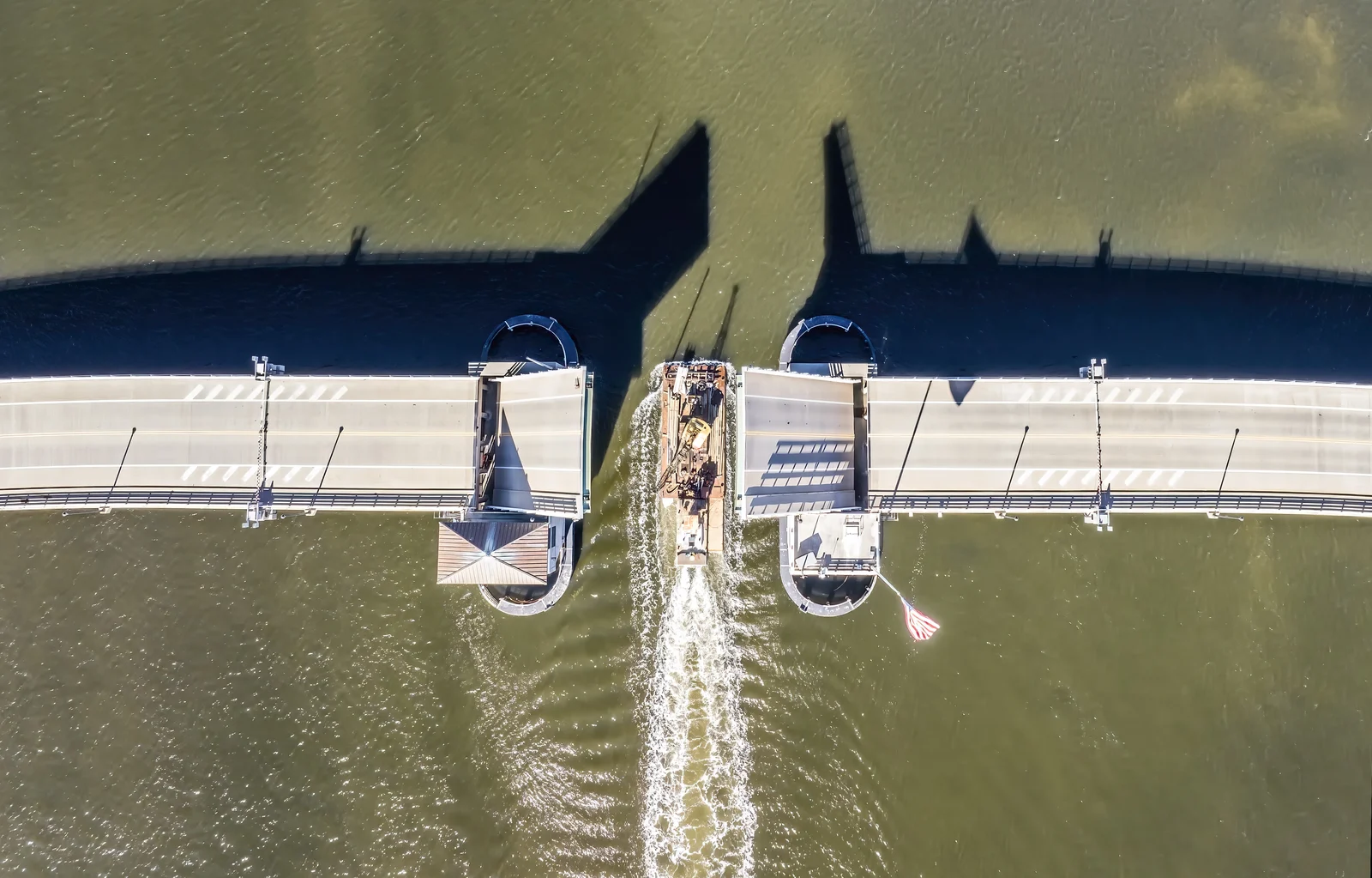 Straight-down drone view of the Mantoloking Bridge with its drawbridge span raised as a boat passes through into Barnegat Bay