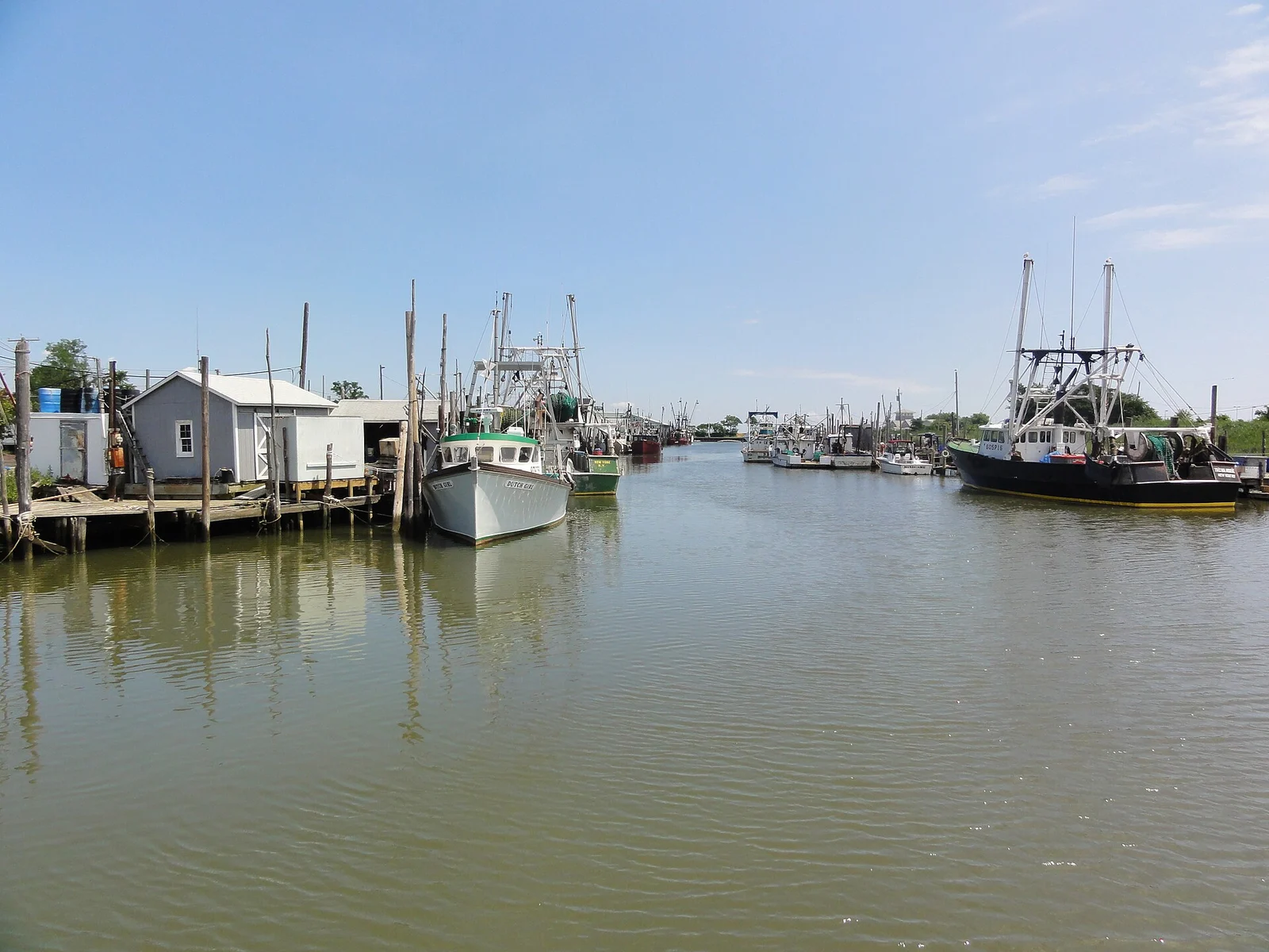 Commercial fishing boats tied up along the wooden docks of the harbor in Belford on a sunny day