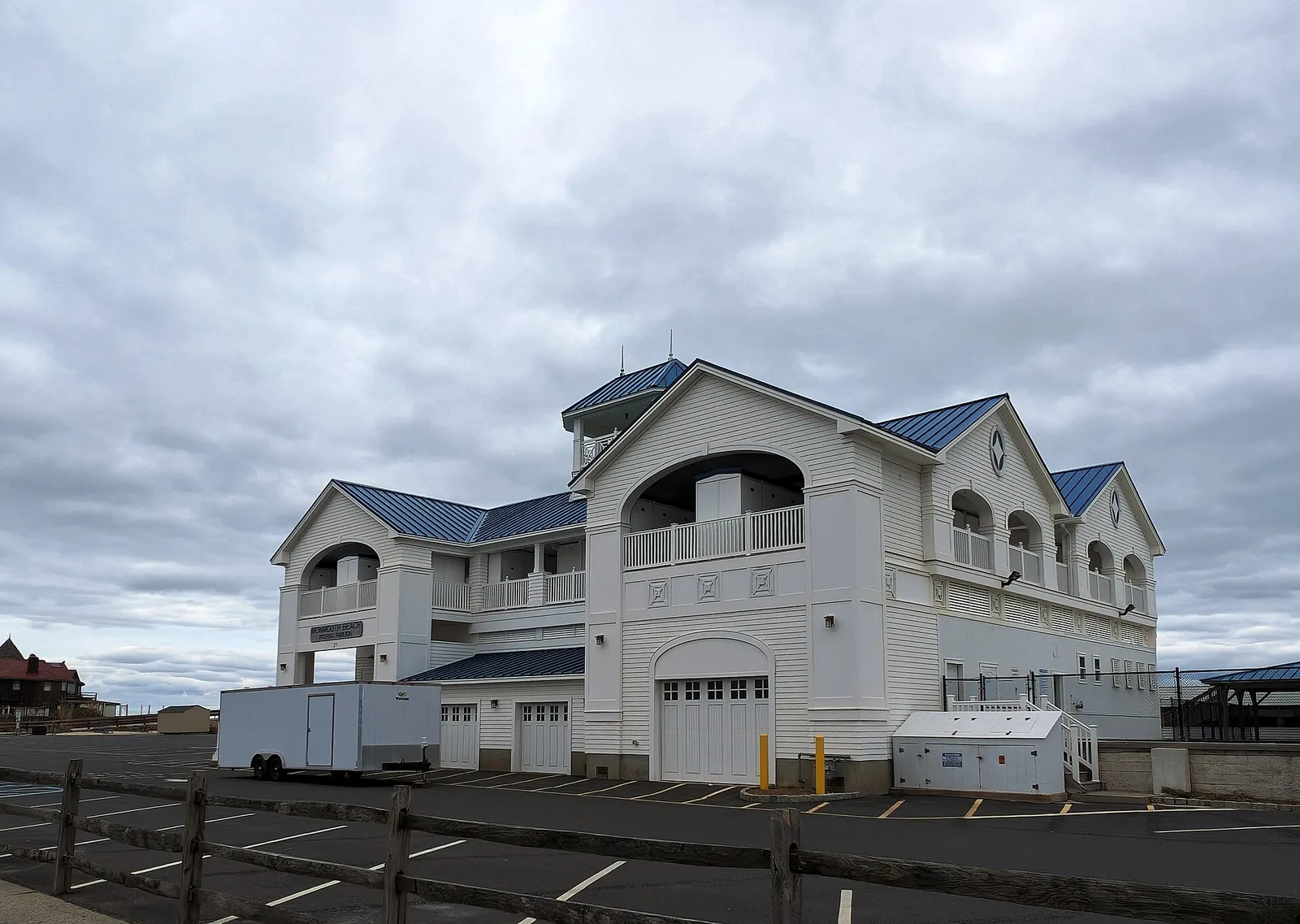 The white Monmouth Beach Bathing Pavilion with its blue roofs and arched balconies beside the beach
