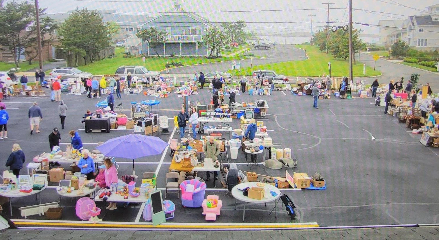 Rows of tables, racks and umbrellas filled with household goods and shoppers browsing at the annual parking lot garage sale at the Cultural Center