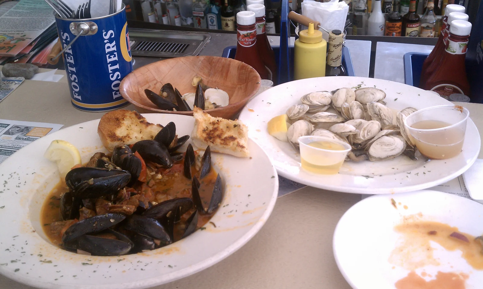 Plates of steamed clams and mussels in red sauce with garlic bread on a table at Kelly's Tavern