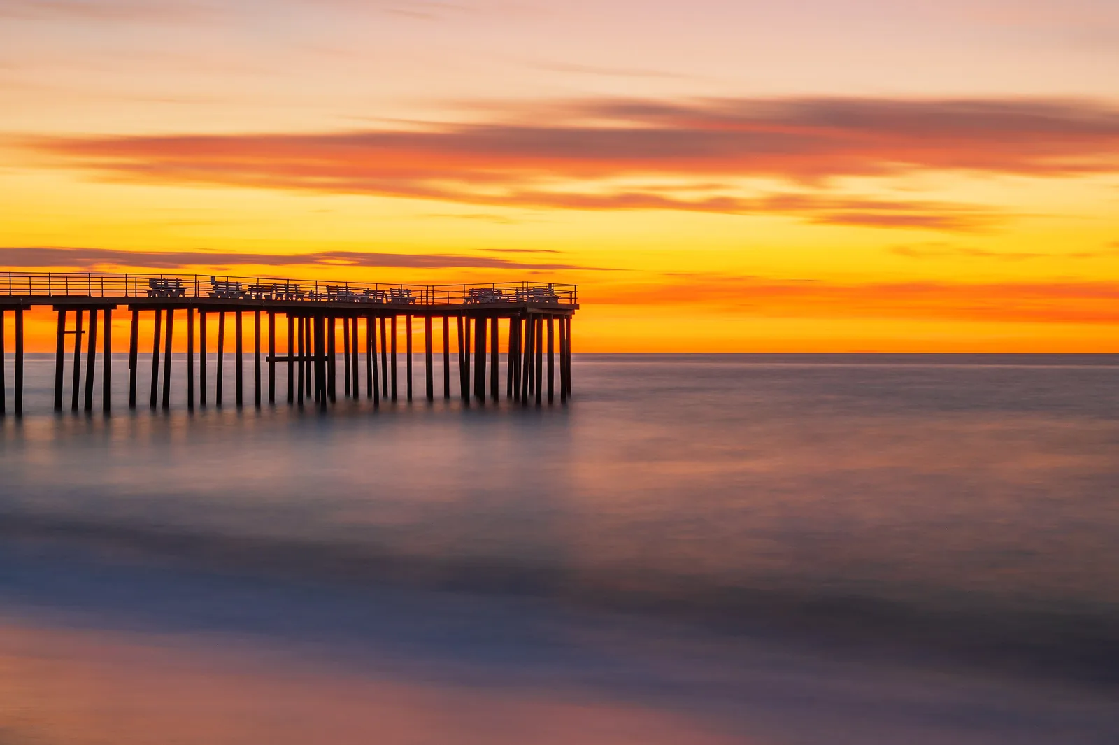 The Ocean Grove fishing pier silhouetted against an orange sky at golden hour