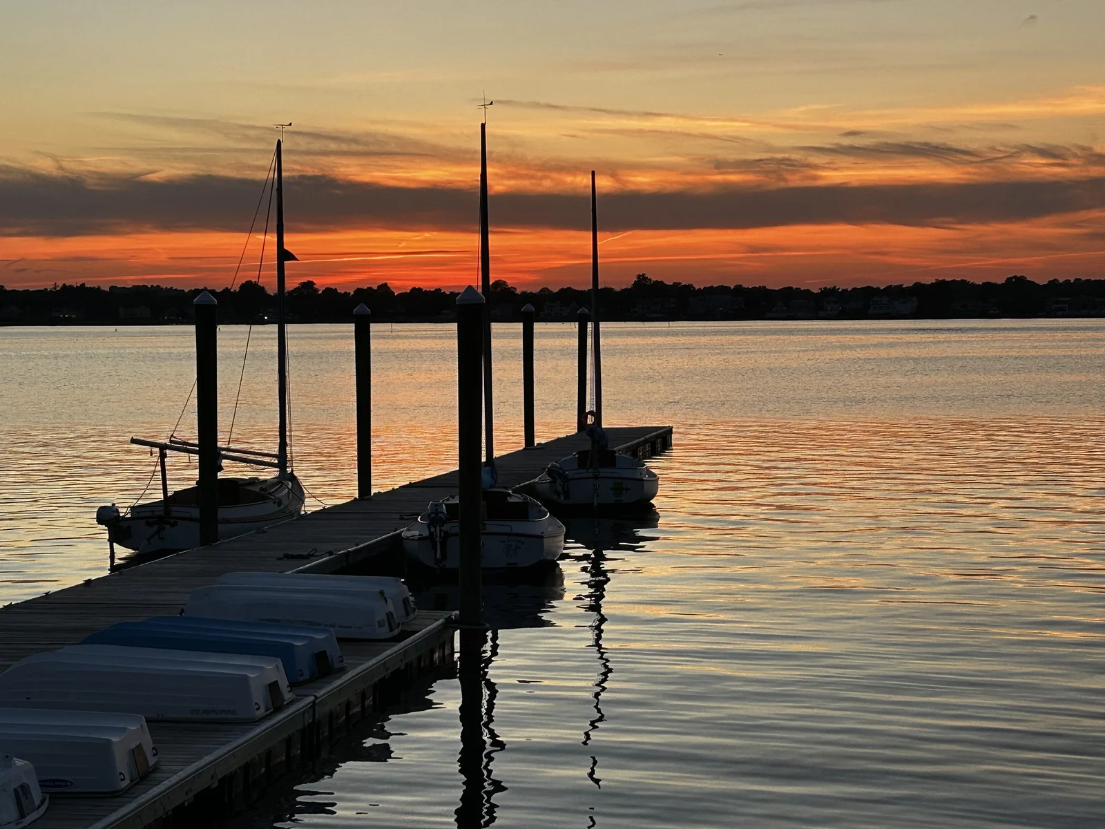 Orange sunset sky over the Shrewsbury River, with sailboat masts and a floating dock at the Shrewsbury Sailing and Yacht Club