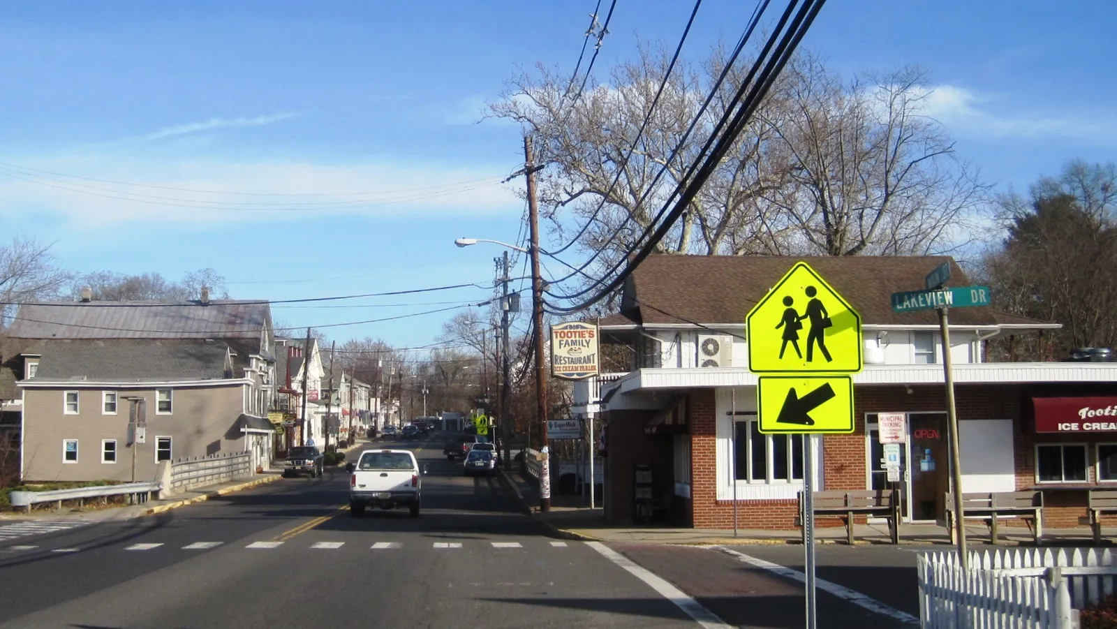 A small-town main street lined with older houses and a brick ice cream bar under a blue sky