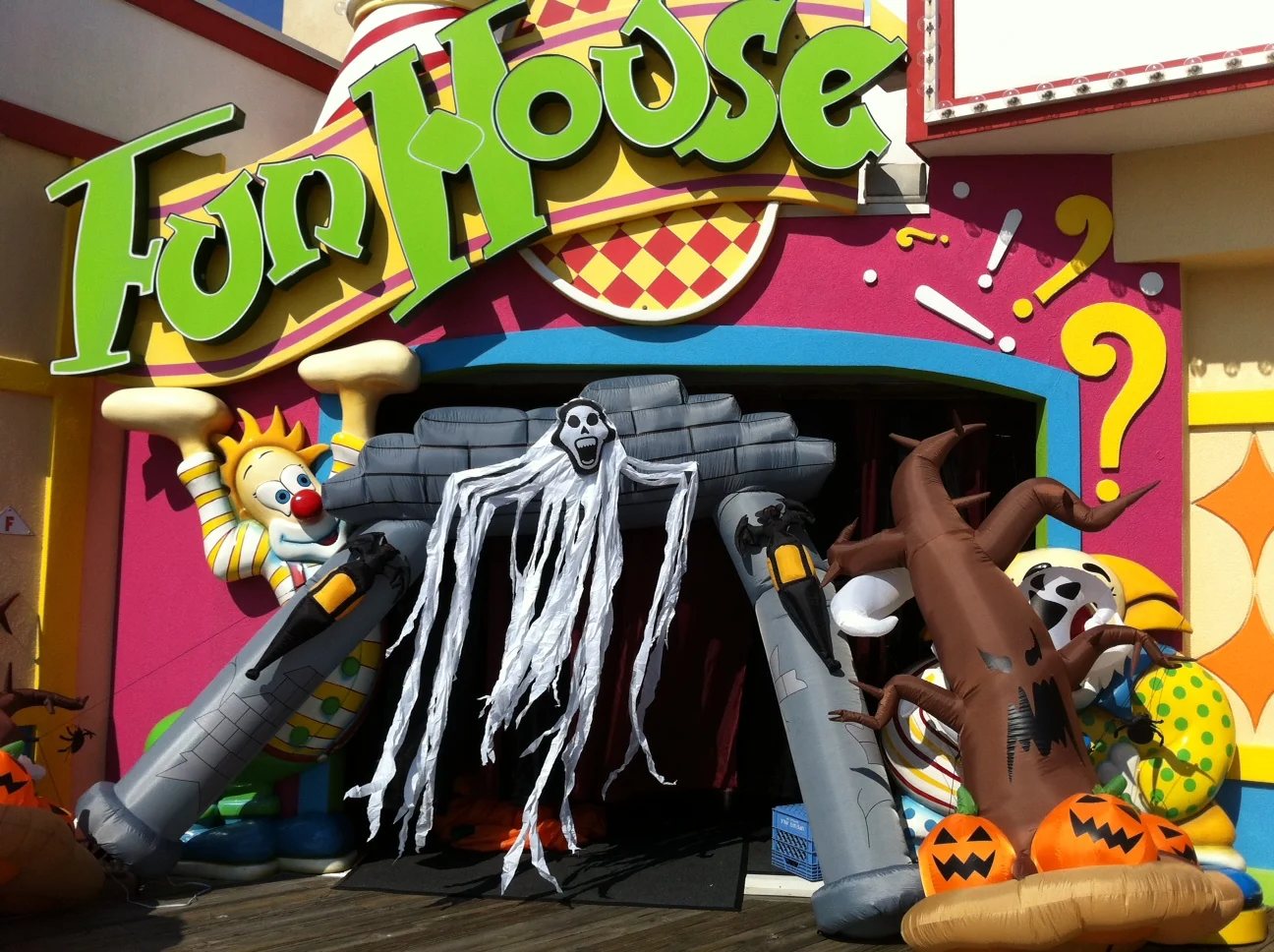 The colorful Jenkinson's Fun House entrance decorated for Halloween with an inflatable haunted arch, a ghost and pumpkins