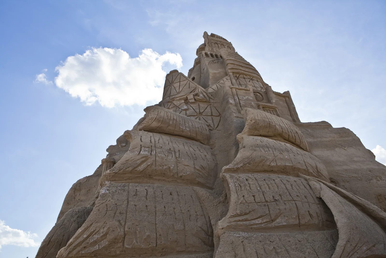 A towering carved sand castle more than 30 feet tall rising against a blue sky