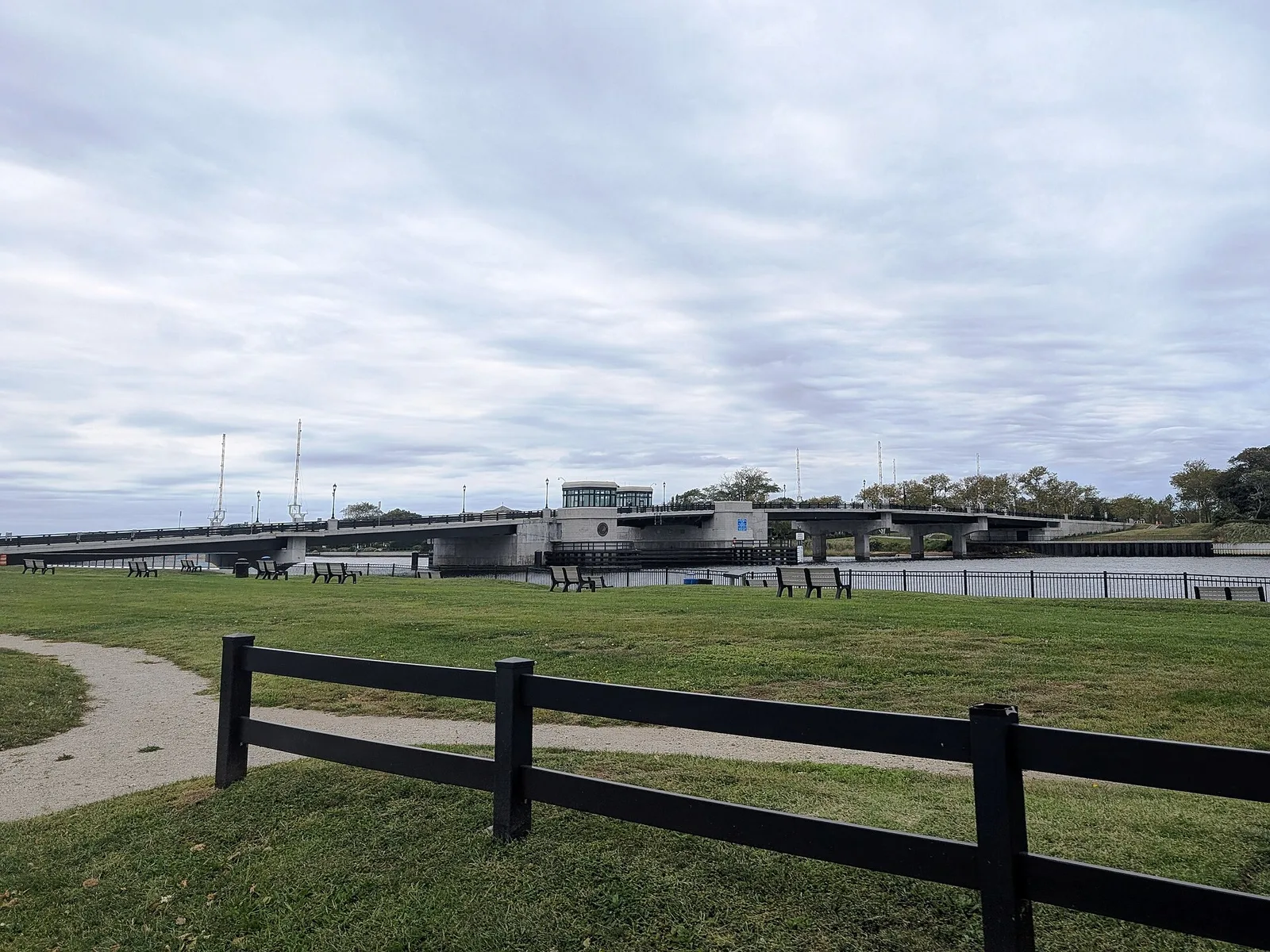 The new Rumson to Sea Bright Bridge across the Shrewsbury River, seen from a waterfront lawn with a dark rail fence