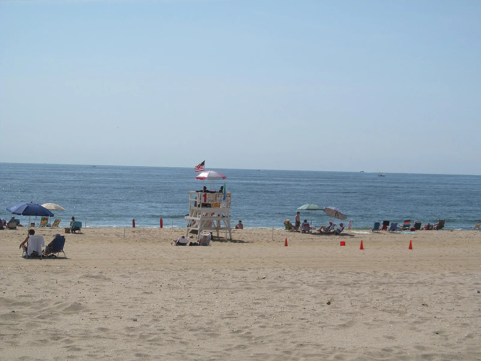 Sea Girt's wide sand beach on a summer day, with a lifeguard stand, umbrellas and the ocean beyond