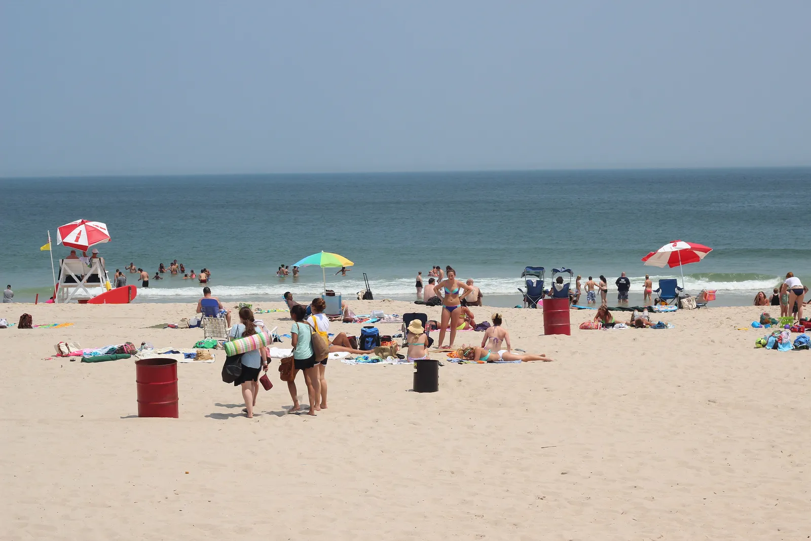 Beachgoers, umbrellas and a lifeguard stand on a sunny Seaside Heights beach