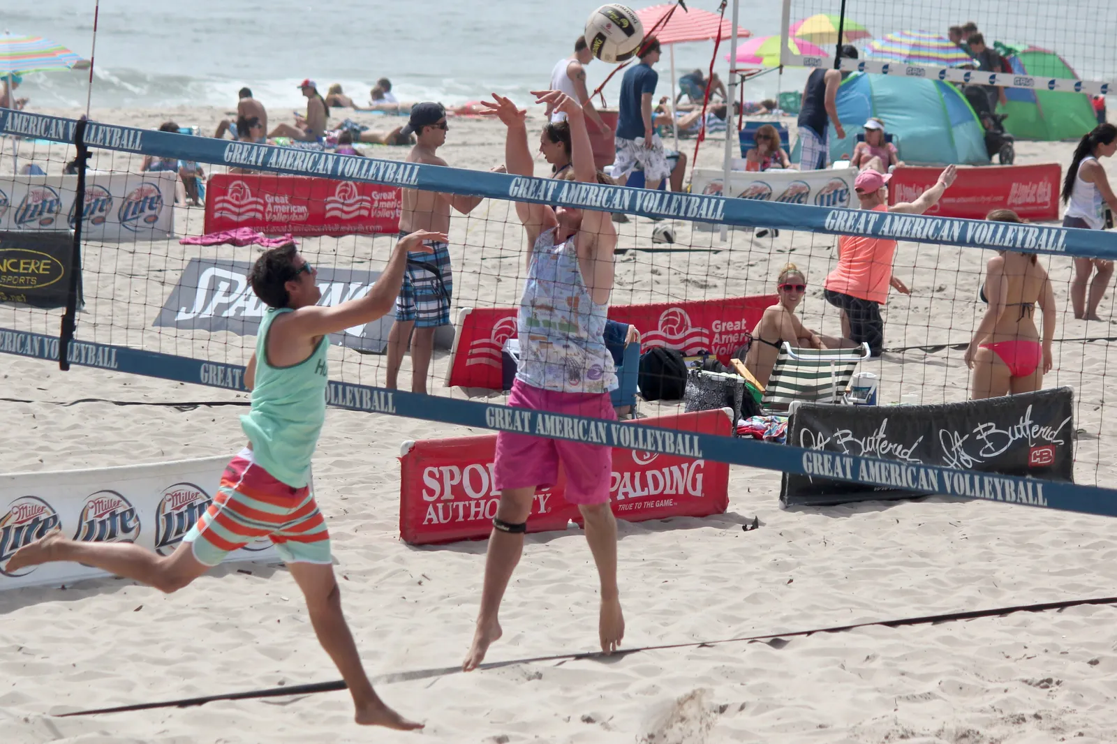 Players leaping at the net in a beach volleyball tournament on the sand