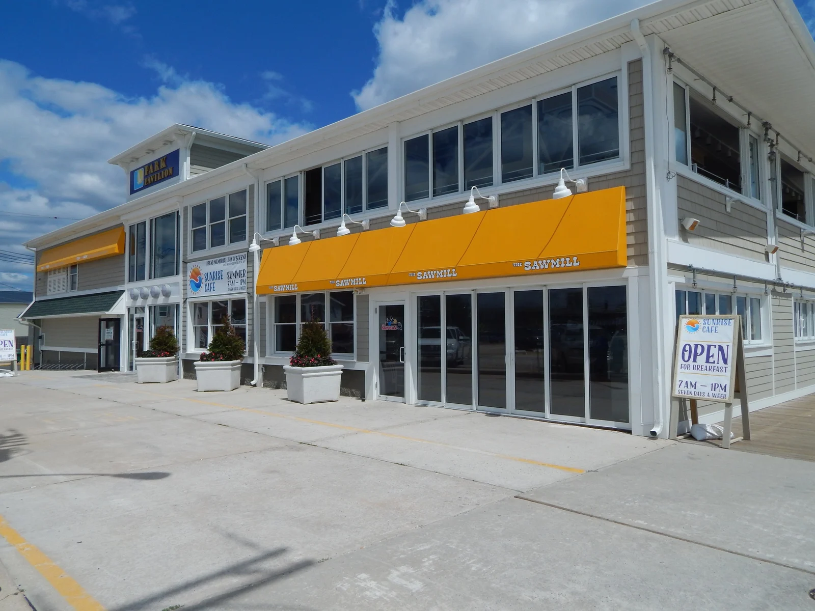 The two-story Park Pavilion building with yellow awnings on the Seaside Park boardwalk, home of The Sawmill