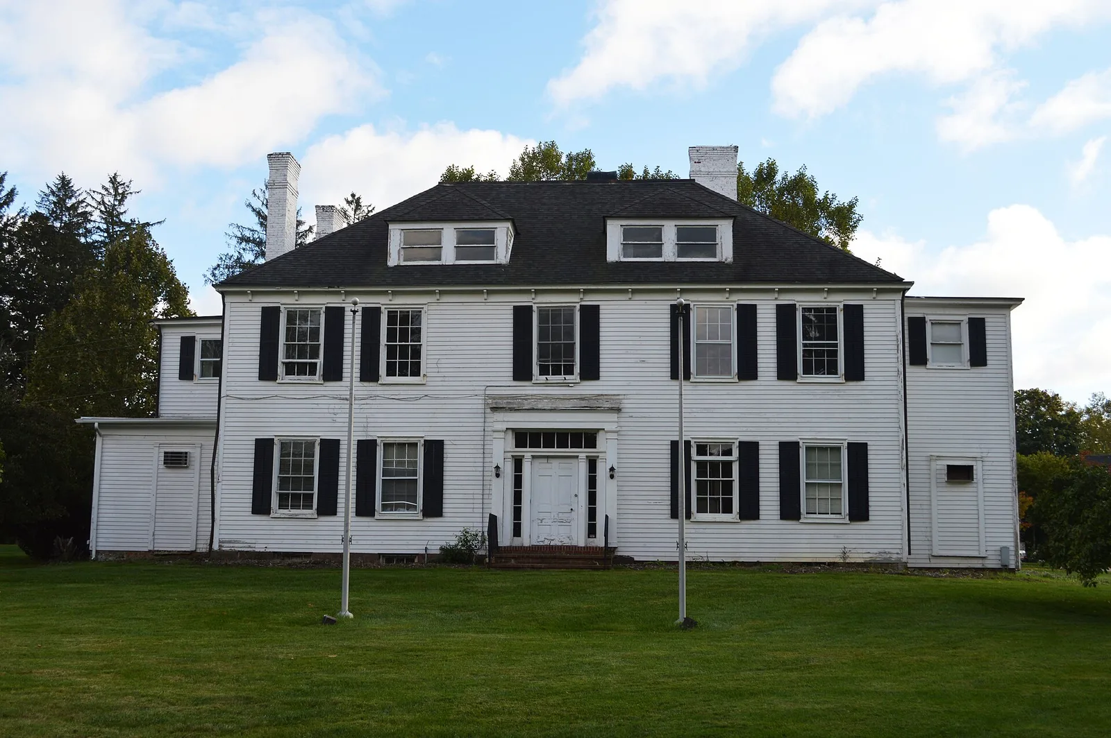 The white three-story Wardell House with black shutters behind a wide lawn