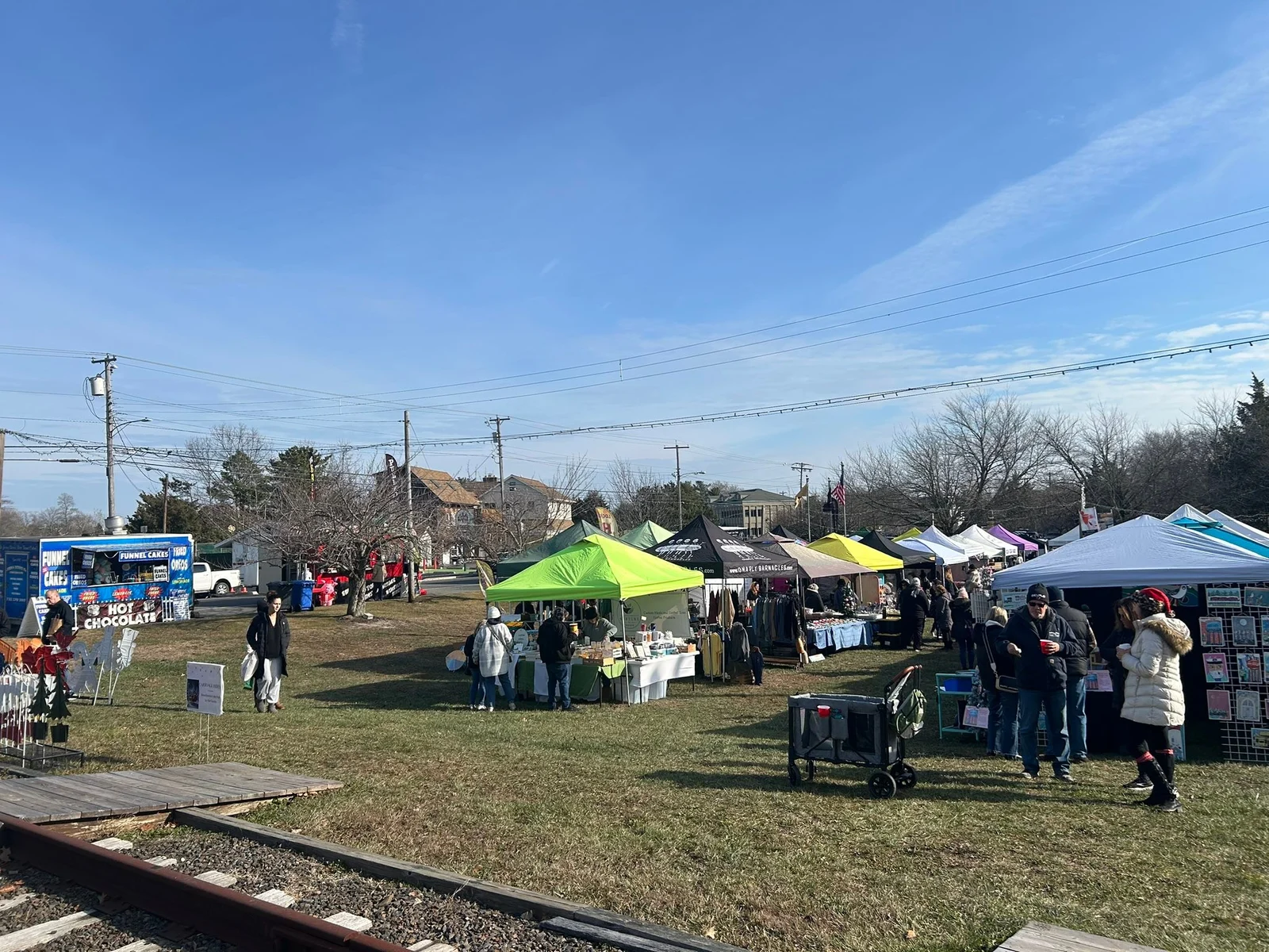 Vendor tents and food trucks on the lawn at Heritage Park beside the old rail line during Holiday Wonderland