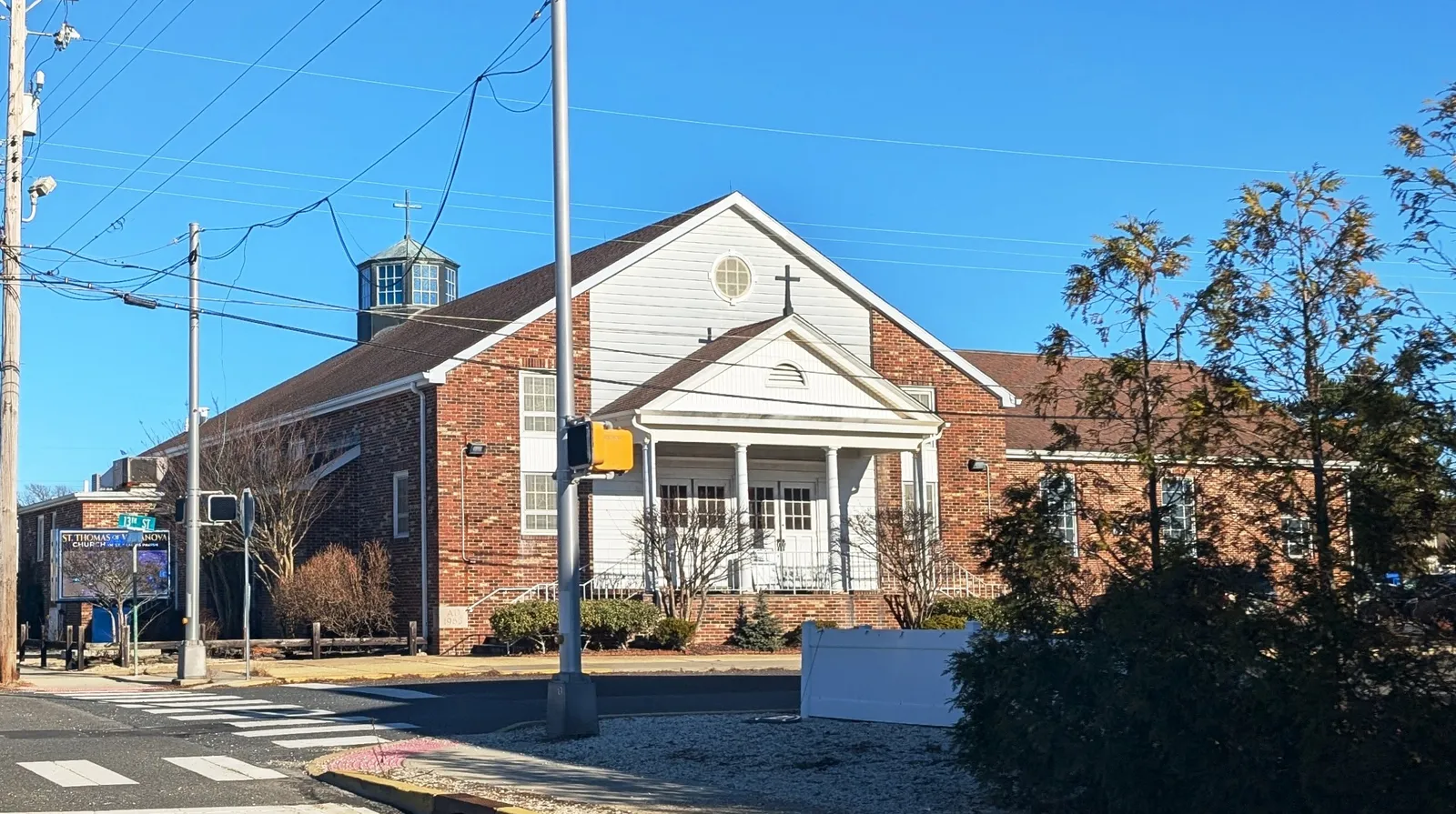 Red brick church with a white columned porch and cupola under a clear blue sky