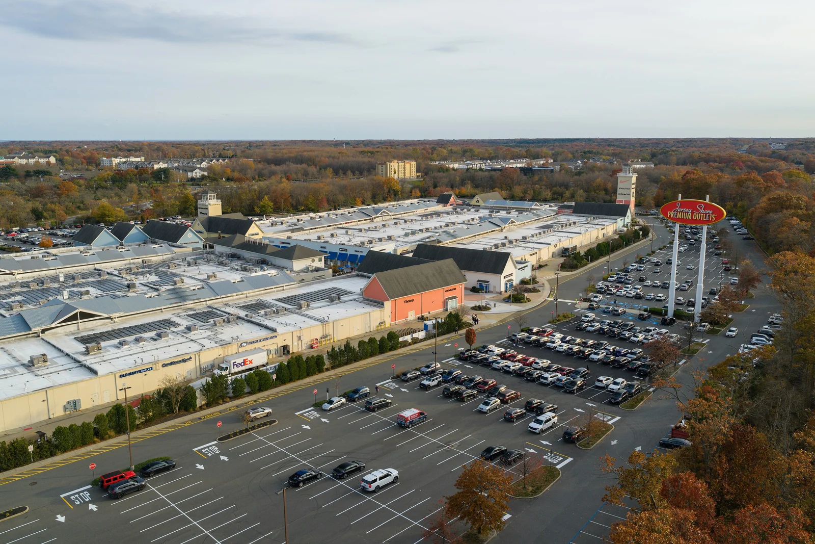 Aerial view of Jersey Shore Premium Outlets with its tall sign, parking lots and fall foliage around it