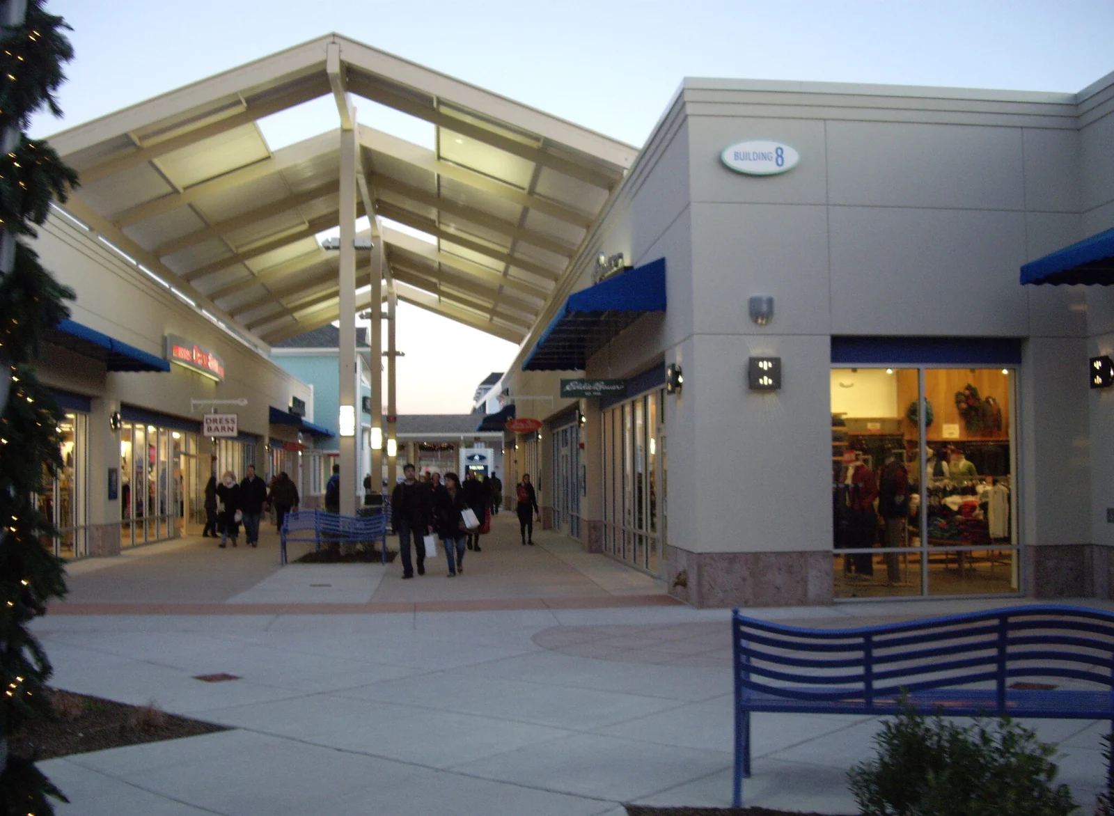 Shoppers walking along a covered open-air walkway between store fronts at Jersey Shore Premium Outlets