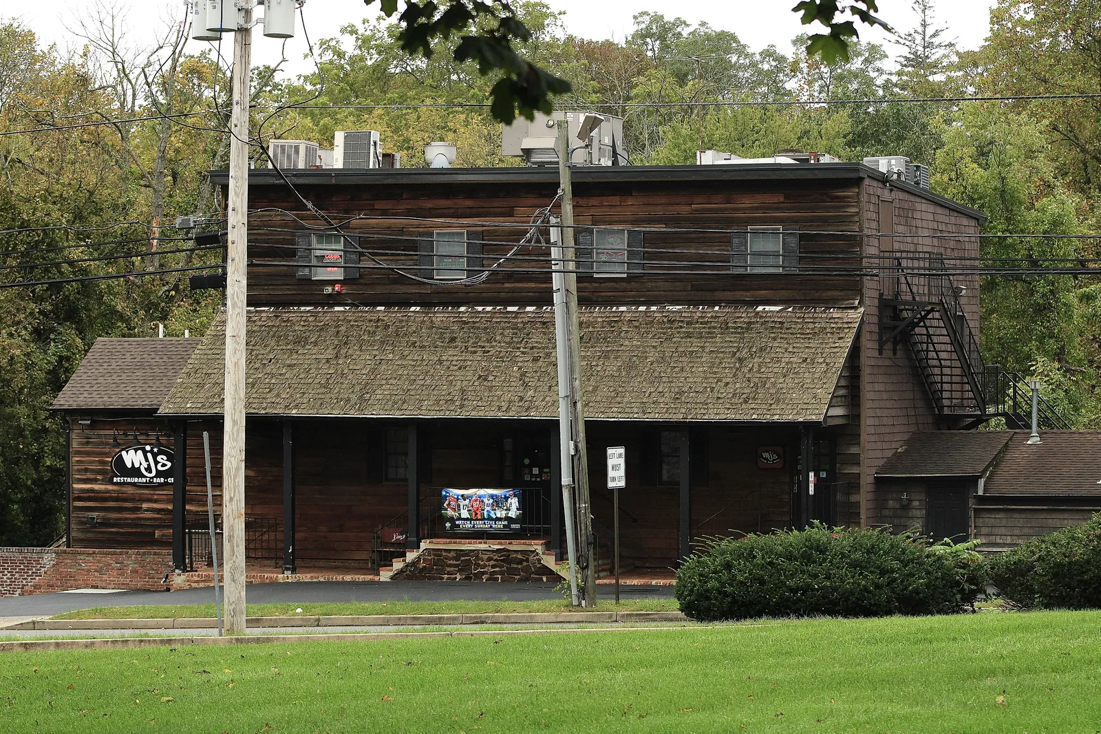 The dark wood Old Mill building behind a green lawn, with trees behind it