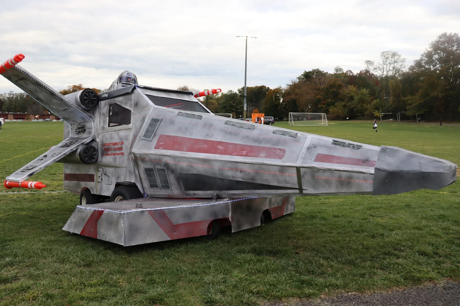 A car decorated as a gray space starfighter parked on the grass at the borough Trunk or Treat