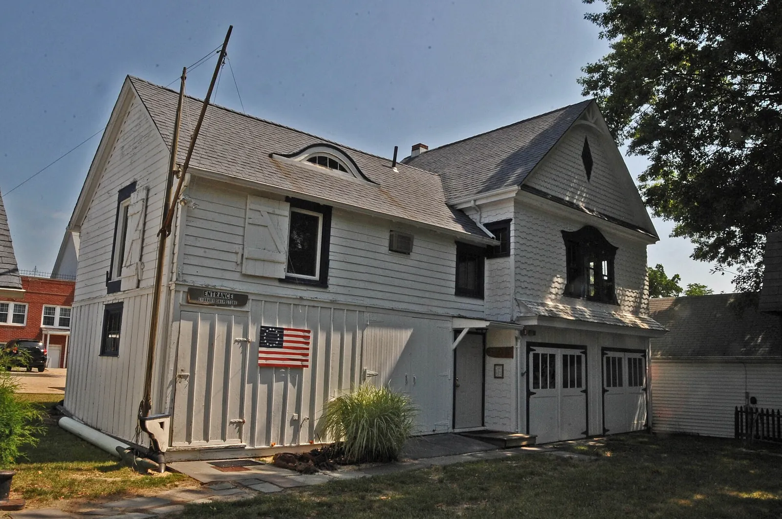 Gray shingled 1868 carriage house with an American flag, now a maritime museum