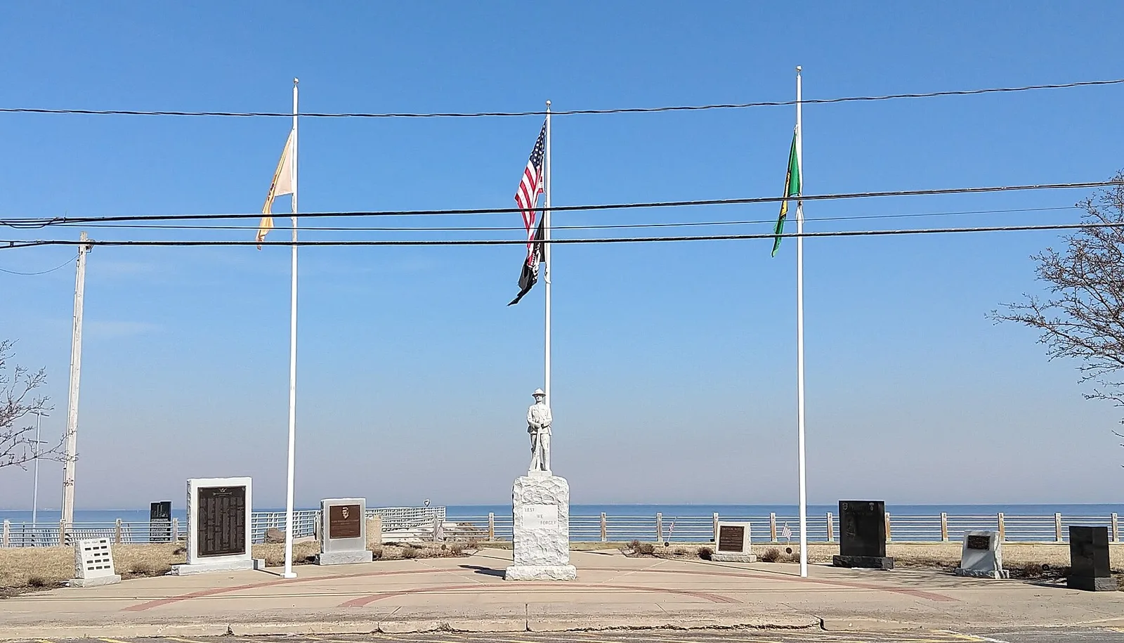 Union Beach's war memorial plaza with flags and a soldier statue beside the bay