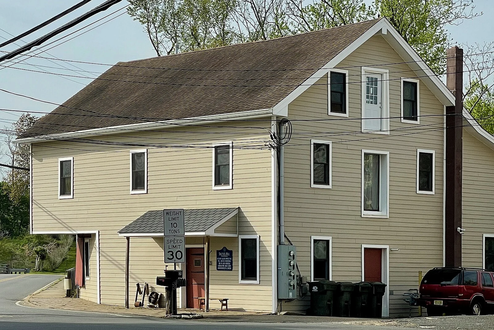 The tall cream-colored clapboard Salter's Mill building with a historic marker out front in the village of Imlaystown