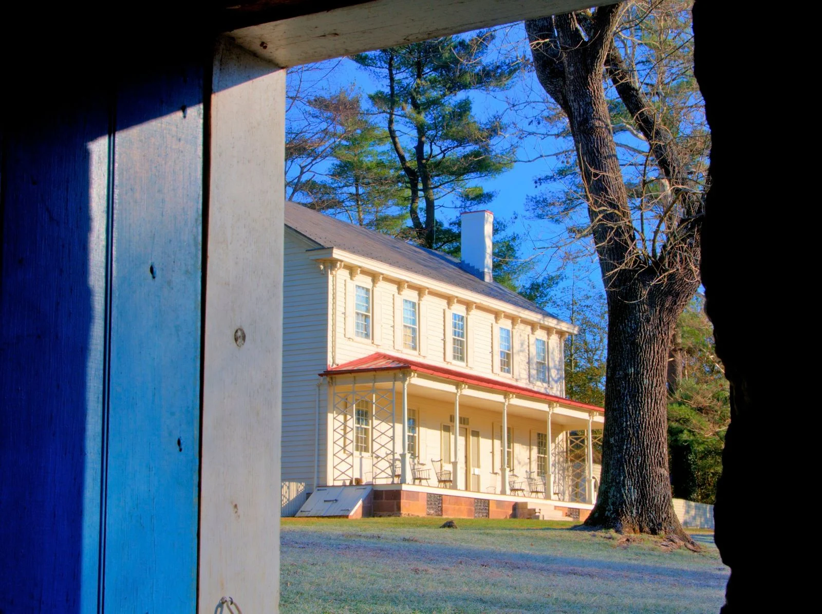 The cream-colored Waln House with its long two-story porch, seen through the open door of the gristmill