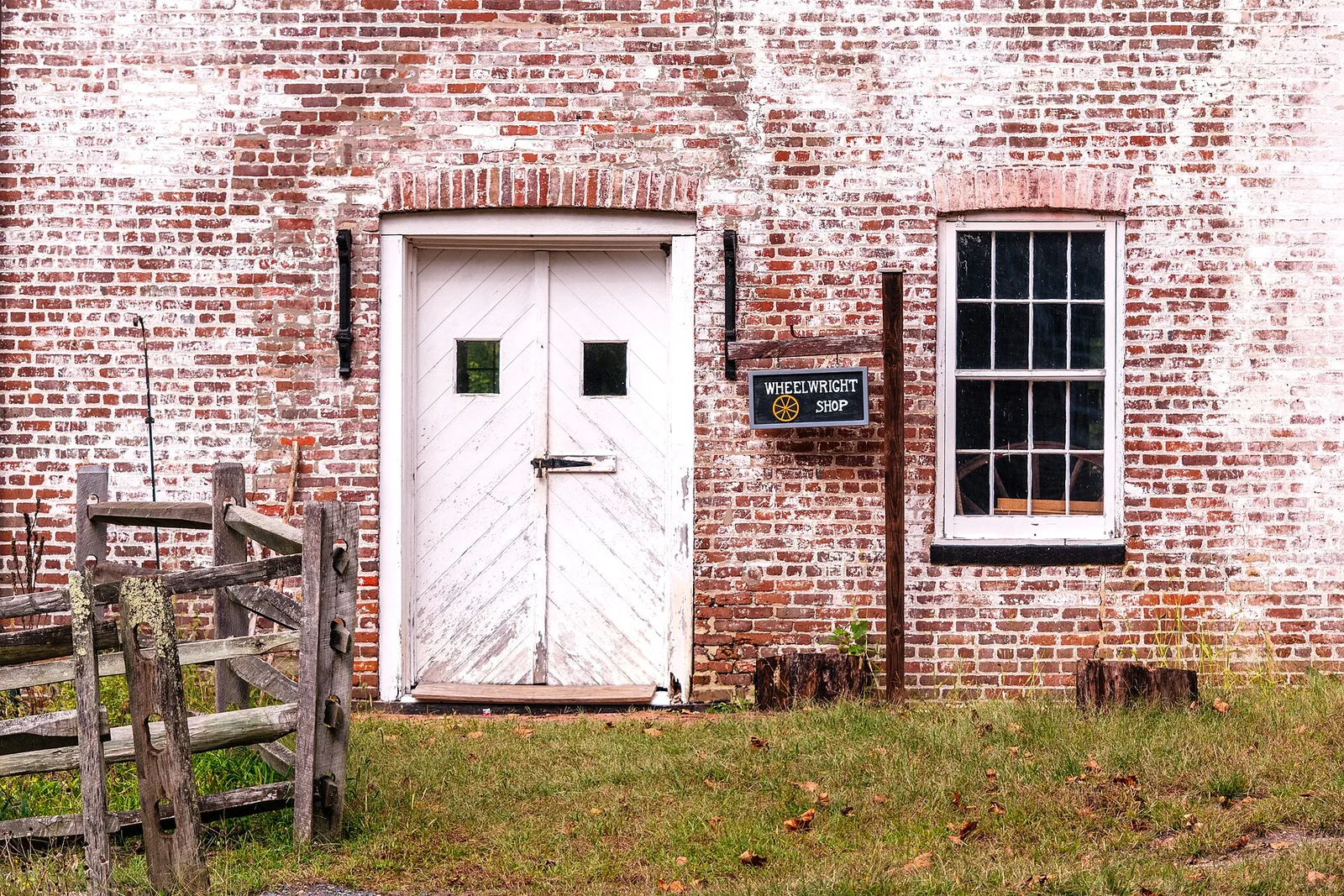 The weathered red brick wheelwright shop with a white wooden door at the Historic Village at Allaire