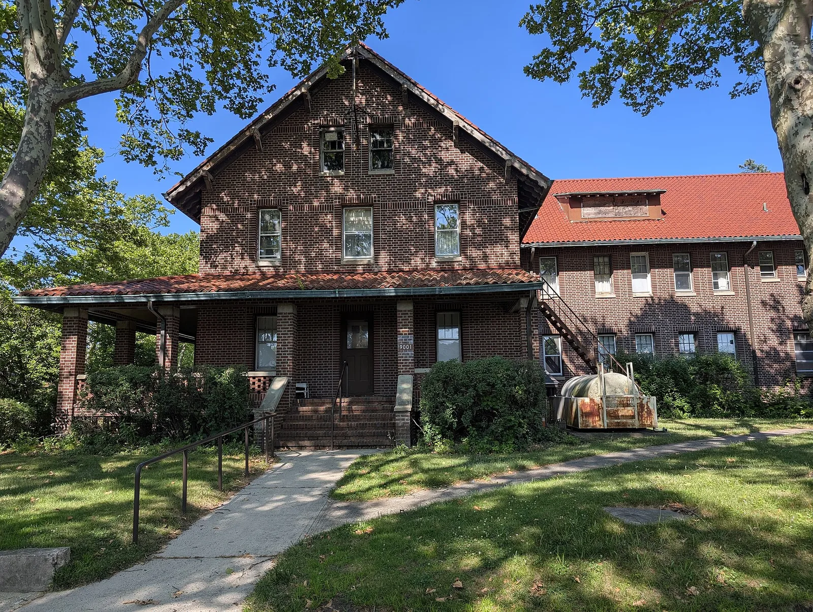 The brick InfoAge Science and History Learning Center building with a red roof and porch at Camp Evans