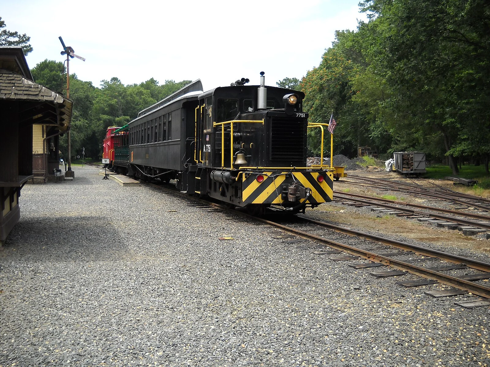 The Pine Creek Railroad's black diesel locomotive 7751 pulling passenger cars along the narrow gauge line