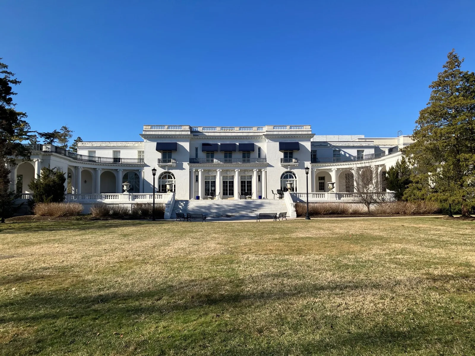 The white Murry Guggenheim House, now a university library, across a wide lawn under a blue sky