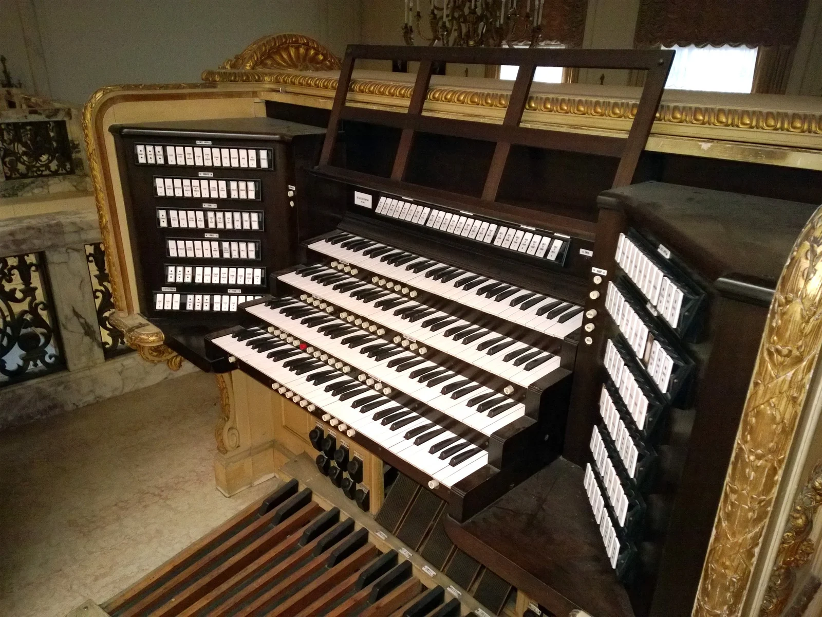 The multi-keyboard console of the pipe organ inside Wilson Hall, set in carved gilded woodwork