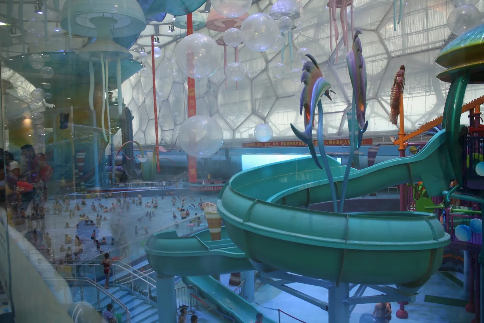 Water slides twisting through a large indoor water park under a glass roof