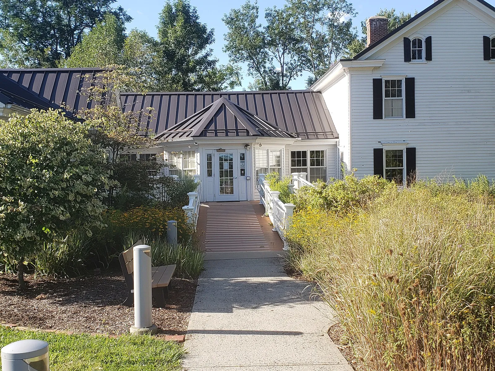 The white Helen C. Fenske Visitor Center with a path and shrubs in front